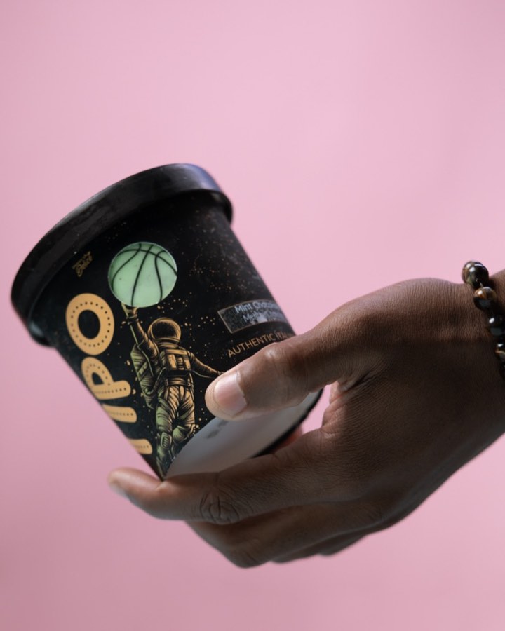 Hand holding a TIPO Mint Chocolate gelato tub against a pink backdrop