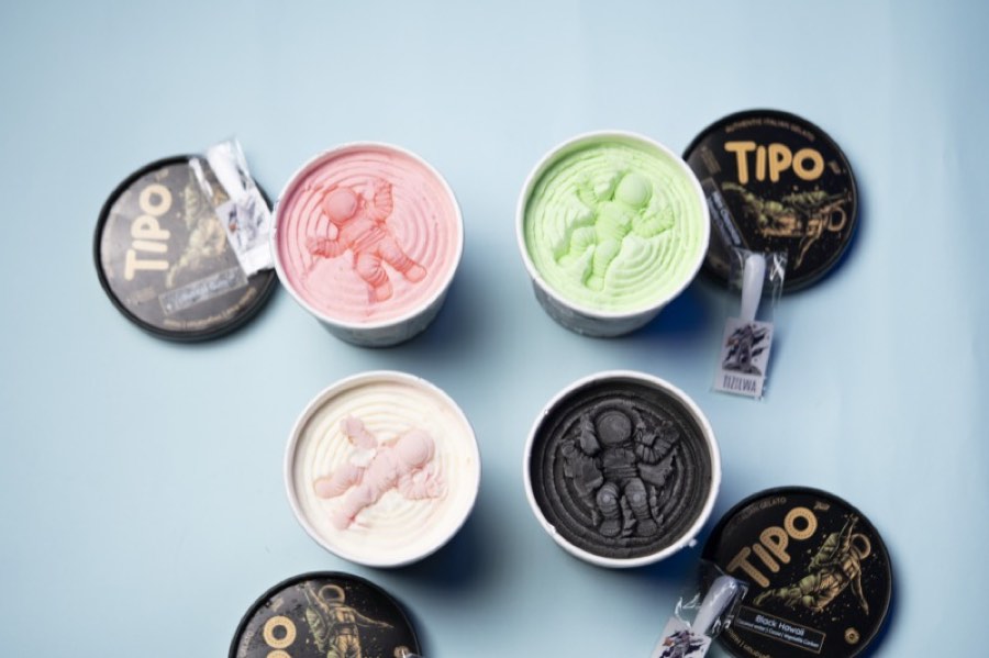 Flat-lay of TIPO gelato tubs with lids and a TIZILWA spoon on a powder blue backdrop